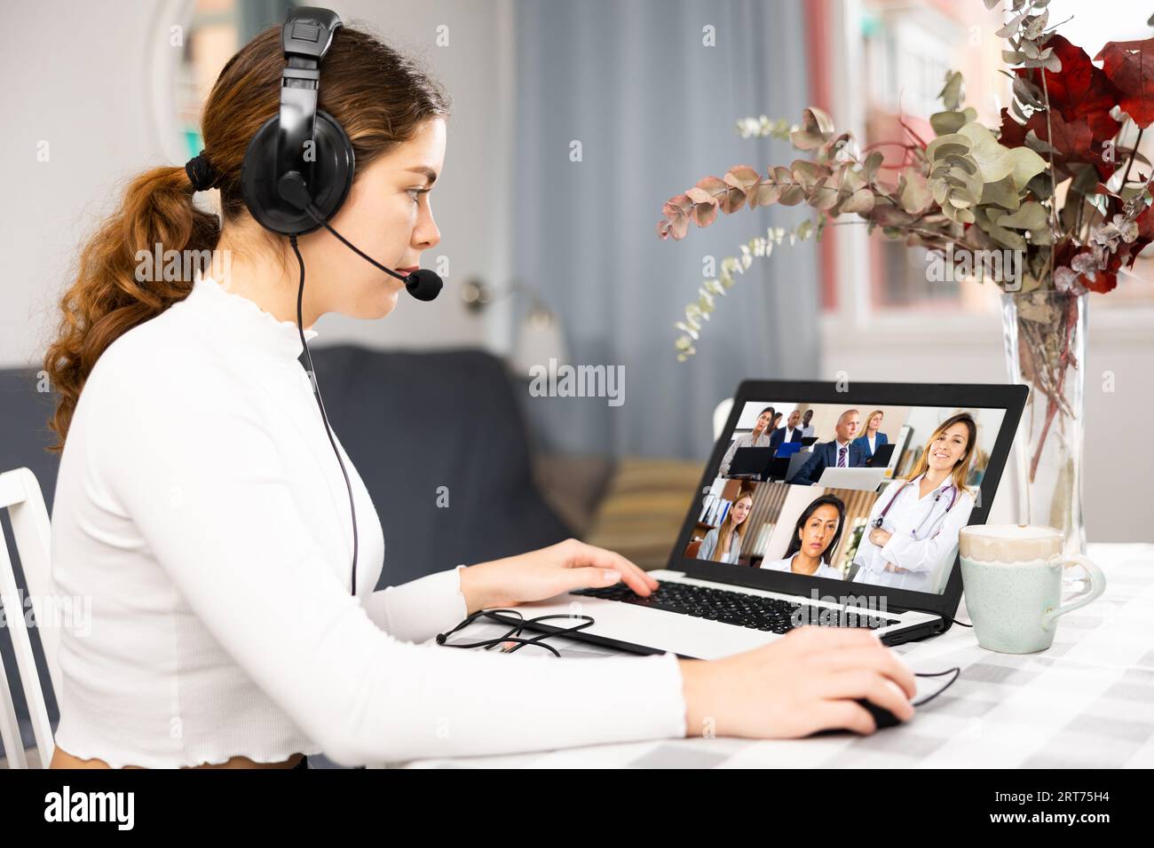 Young having conversation with her colleagues during video call Stock Photo