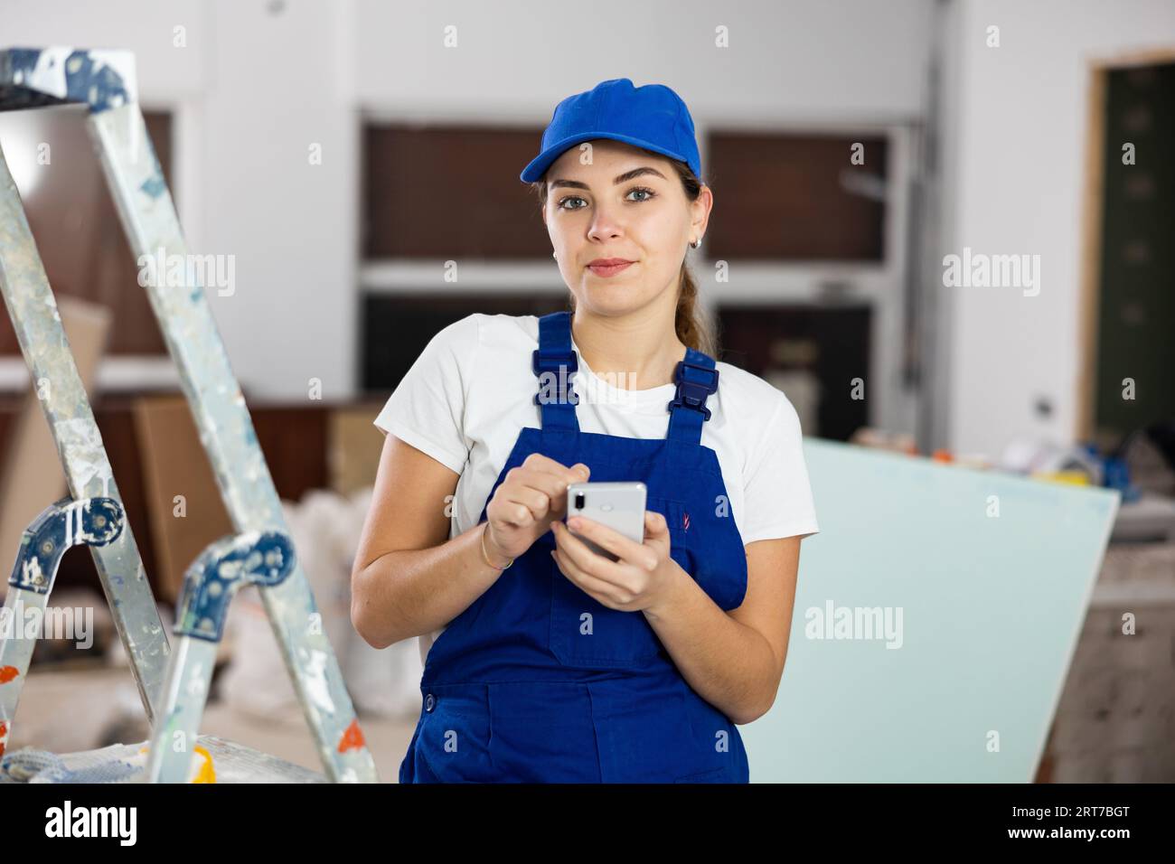 Female construction worker using smartphone in apartment Stock Photo