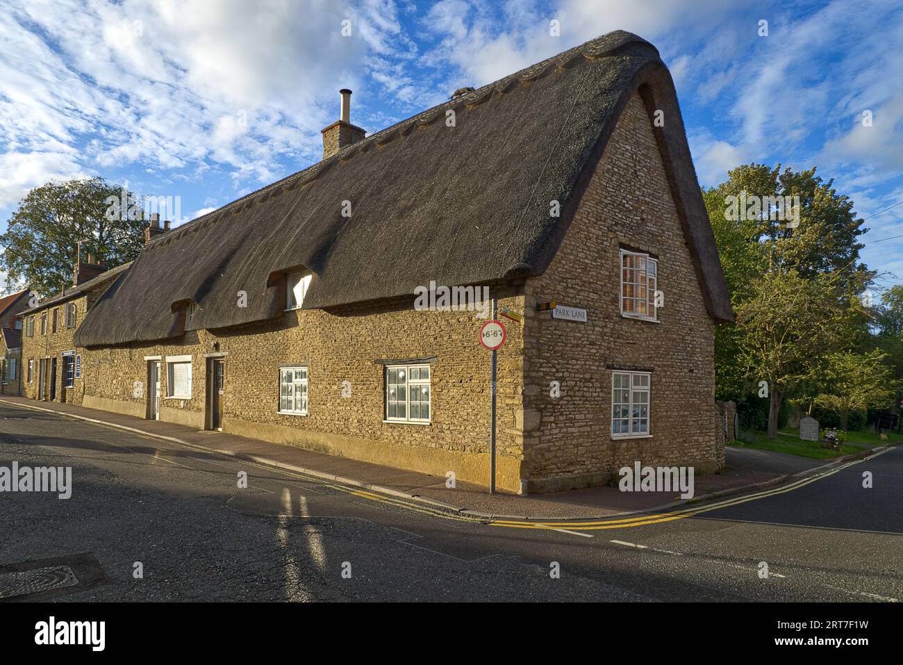 Pretty thatched cottage and chemist shop at the junction of Park Lane and the High Street in the Bedfordshire village of Sharnbrook, England, UK Stock Photo