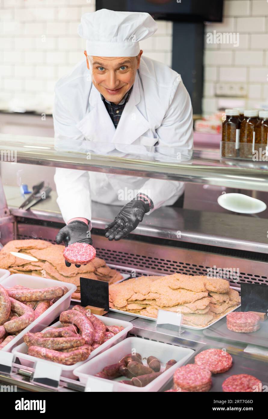 Diligent female butcher showing beef burger patties in butcher shop Stock Photo Alamy
