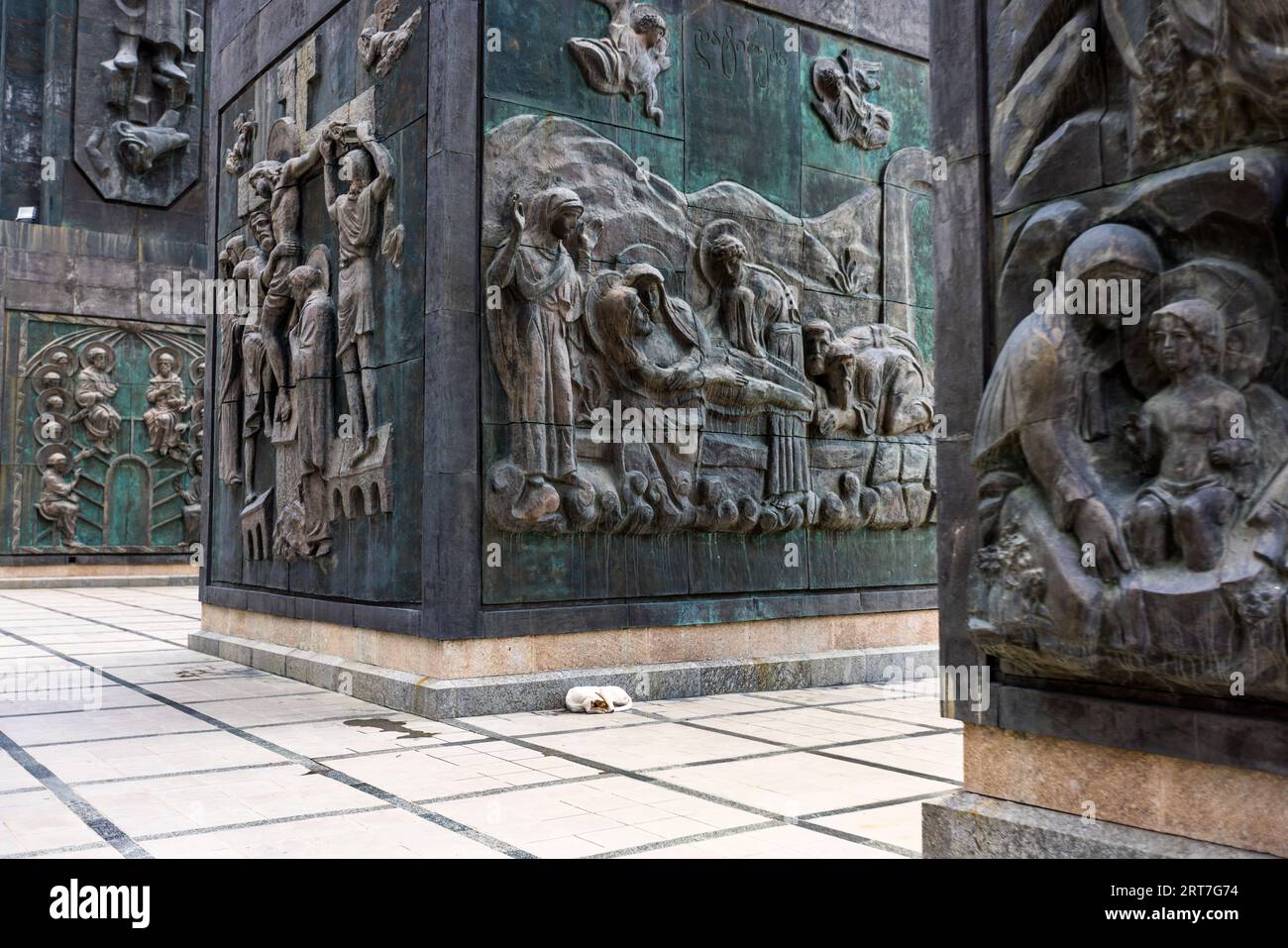 A dog dozes in the Chronicle of Georgia, a monumental sculpture near Tbilisi, the capital of Georgia. 16 columns rise 35 meters high. Biblical scenes are depicted in the lower part. Above them are depicted personalities significant for the history of Georgia. The monument was begun in 1985 by the sculptor Zurab Zereteli and has not yet been completed. Stock Photo