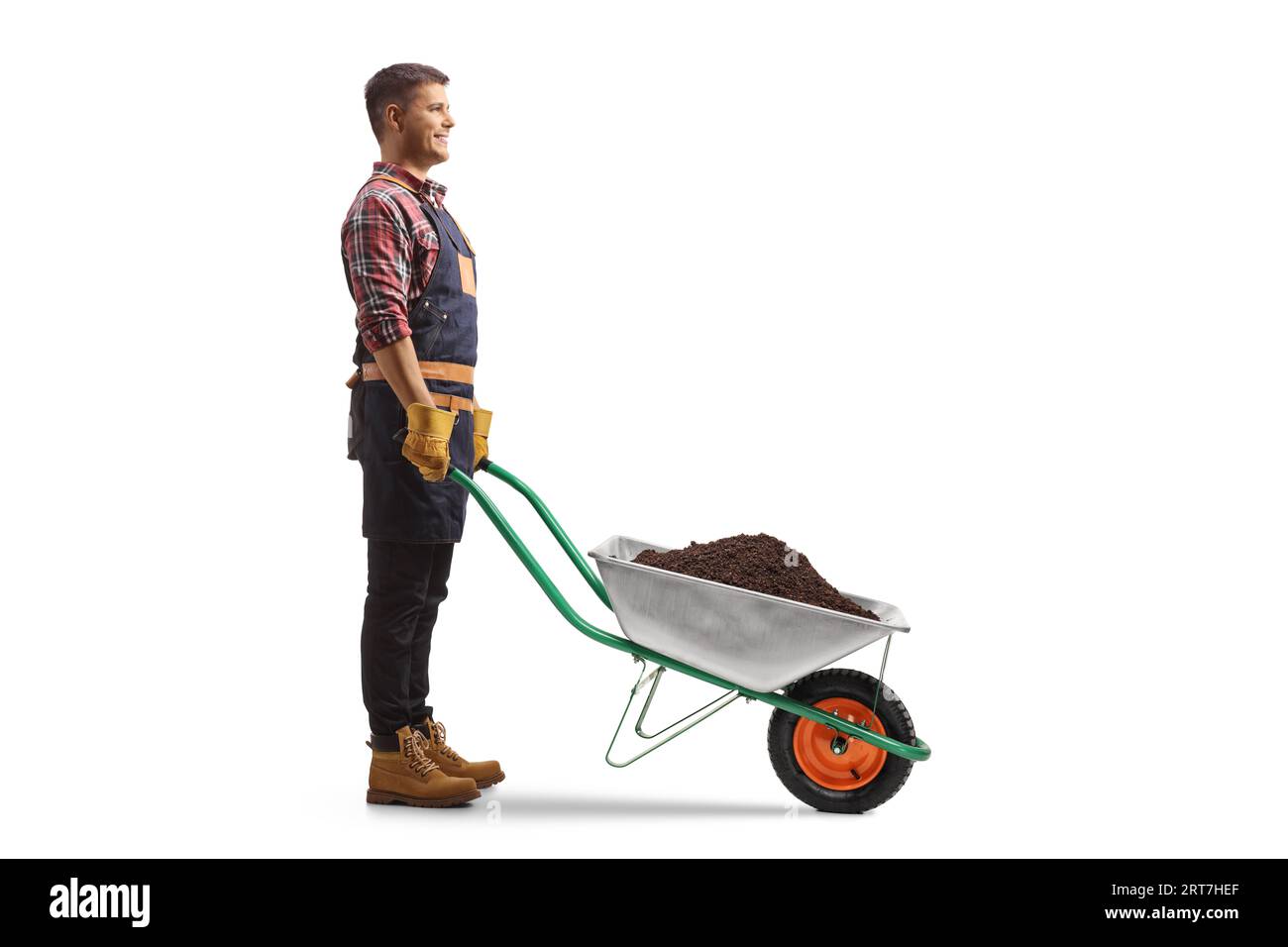 Full length profile shot of a farmer standing with wheelbarrow full of earth isolated on white background Stock Photo