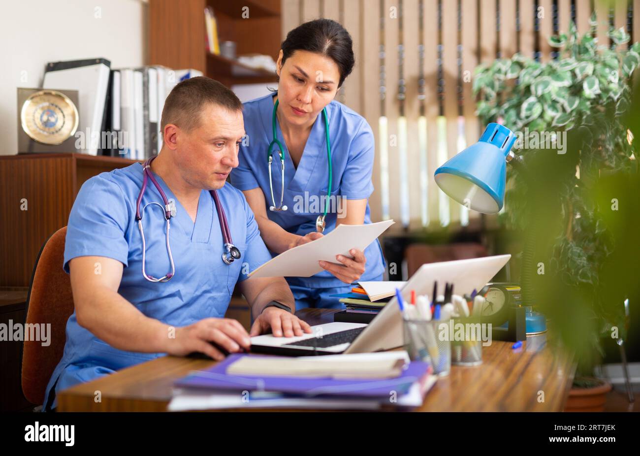 Two focused physicians working with case histories on laptop Stock Photo