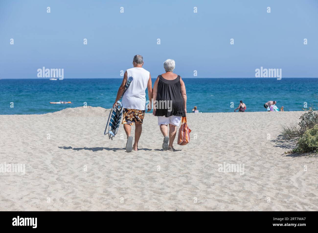 A couple walking onto a sandy Mediterranean beach at Le Barcares, South of France Stock Photo