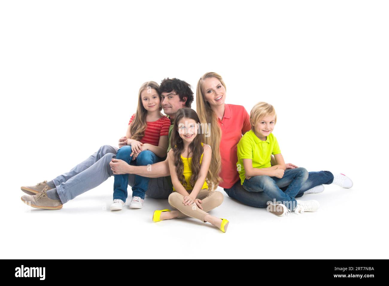 Portrait of happy family with three children sitting on the floor at studio isolated on white background Stock Photo