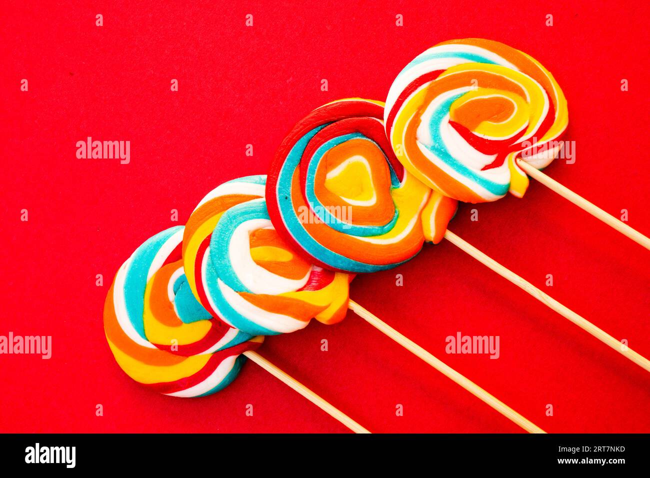 Colorful spiral lollipop candy on stick. On a red background. Stock Photo