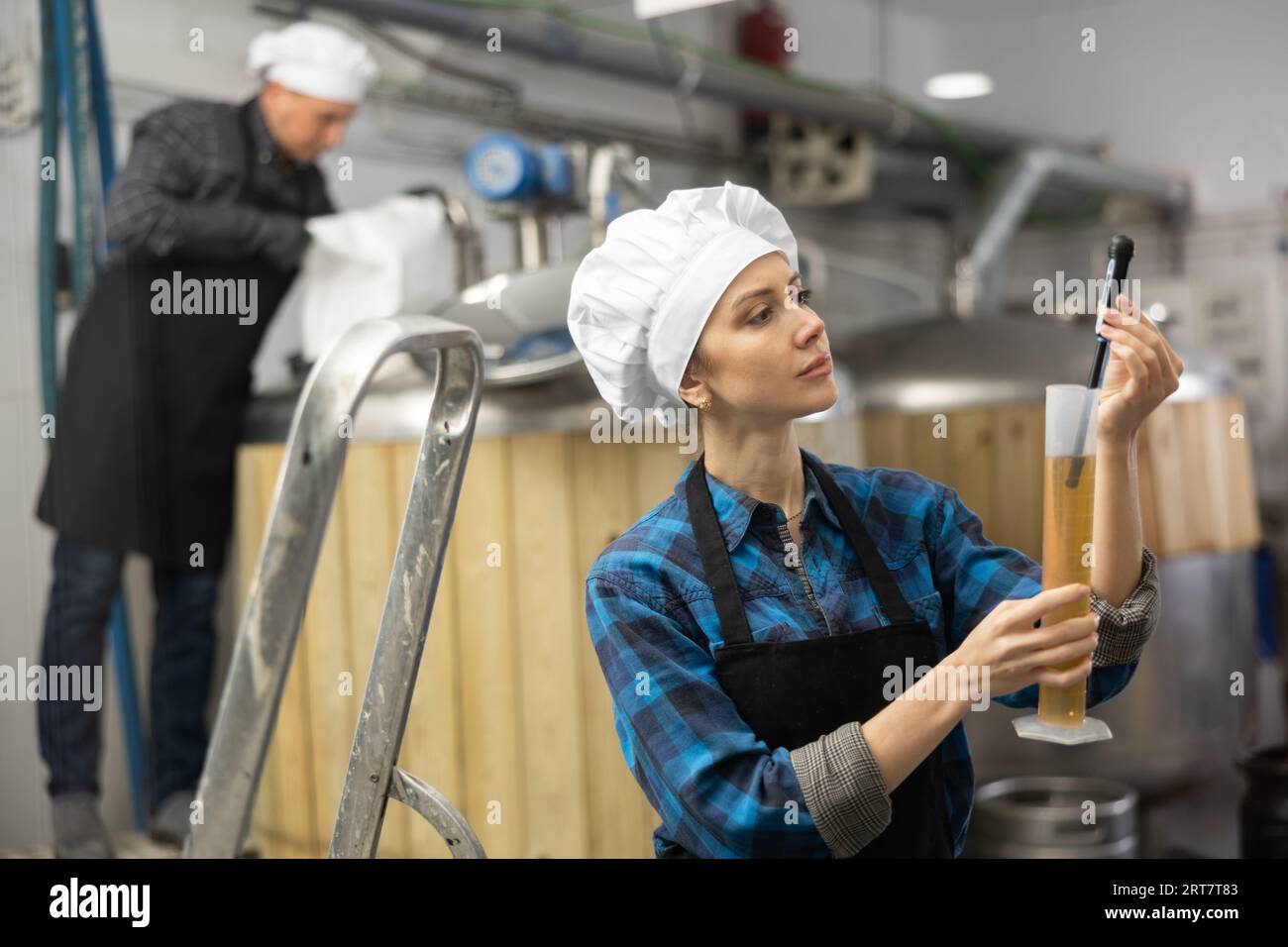 Woman brewmaster measuring beer with alcoholometer Stock Photo