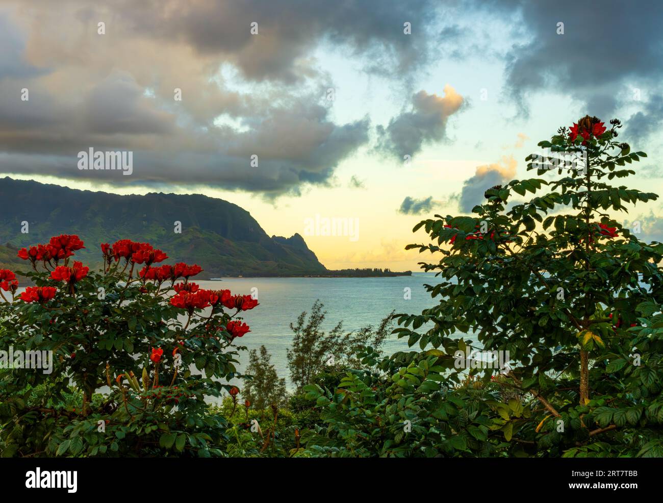 Rising sun illuminates clouds over the mountain peaks of Na Pali coast