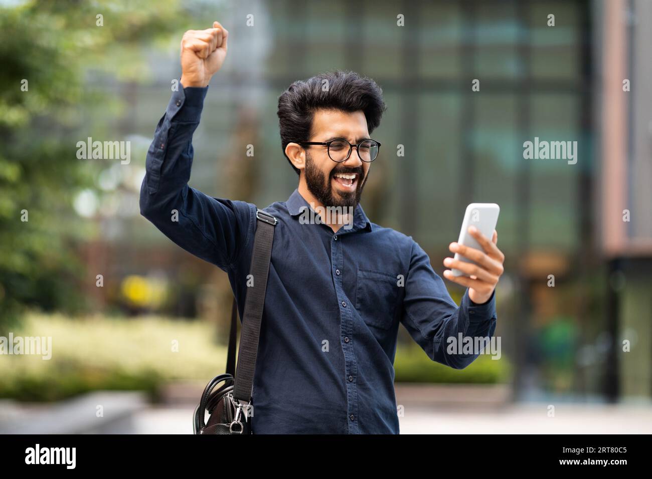Excited eastern businessman looking at phone screen, gesturing Stock Photo