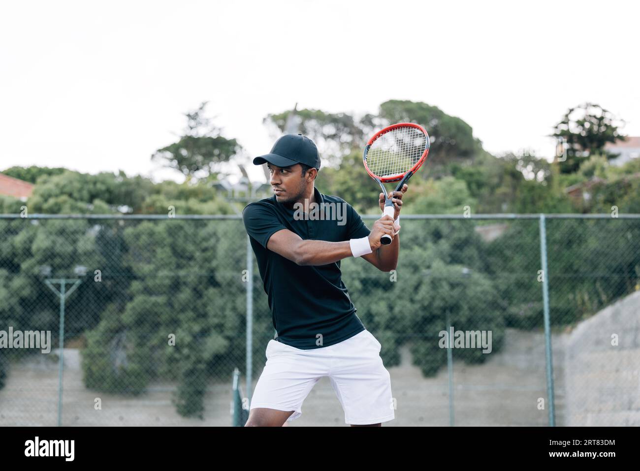 Tennis player with racket practicing at outdoor court Stock Photo