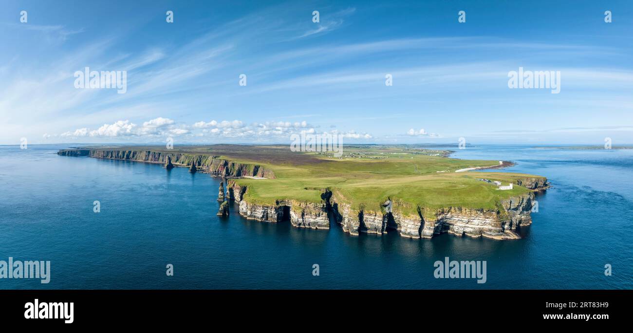 Aerial panorama of the rugged coastal landscape at Duncansby Head with the lighthouse on the right, the Duncansby Stacks rock formation on the left Stock Photo