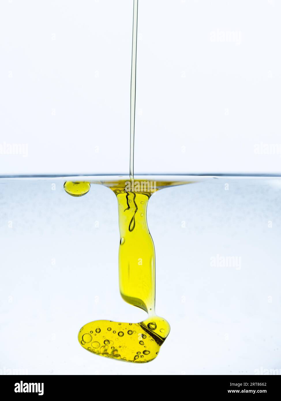Detail of dash of olive oil drops gliding into glass of water isolated