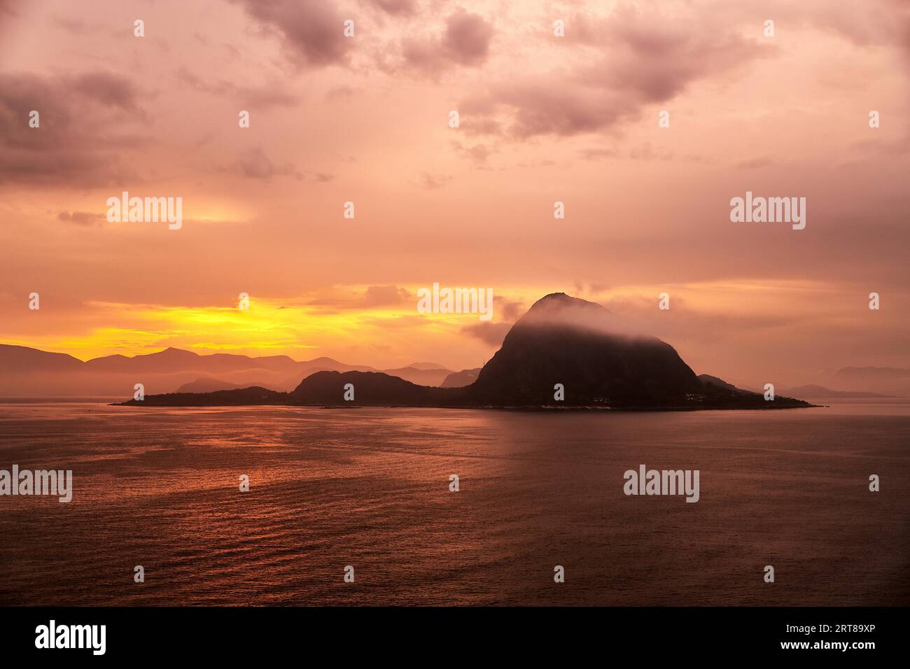 Rock Hessa nearby Alesund Norway in the ocean with clouds in sunrise Stock Photo