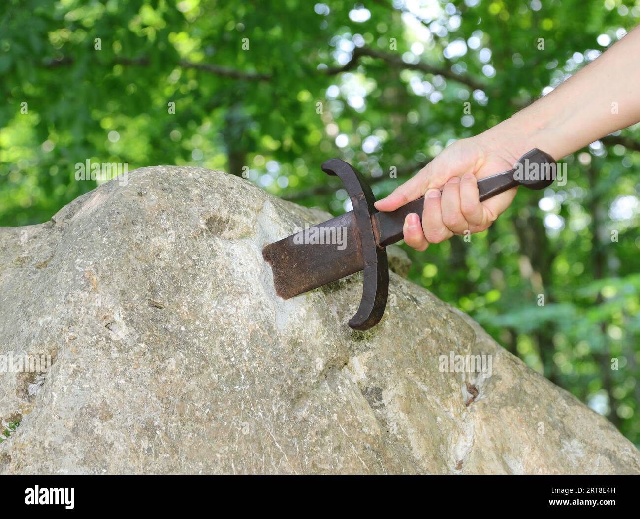 hand of the knight trying to extract the magic sword Stock Photo
