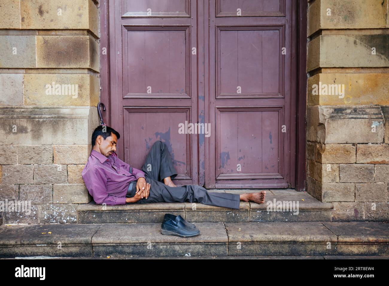 Mumbai, India, August 5 2017: A man has a quick sleep on some building steps on a hot day in Colaba, Mumbai, India Stock Photo