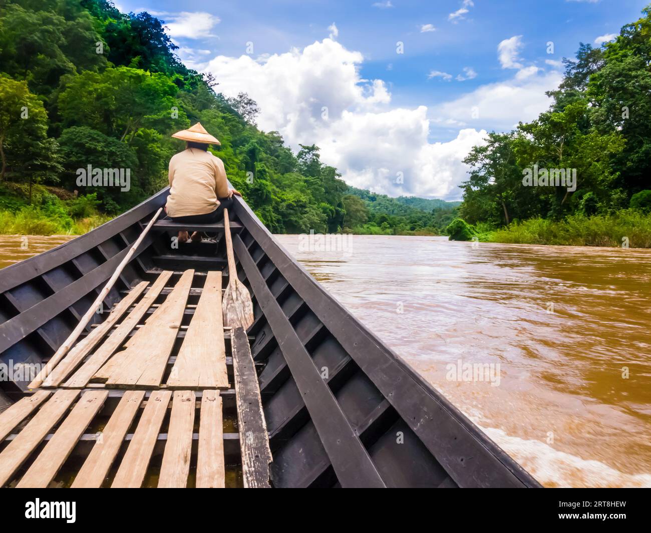 Helmsman with traditional cone hat sails on Pai river with long tail boat, Thailand Stock Photo