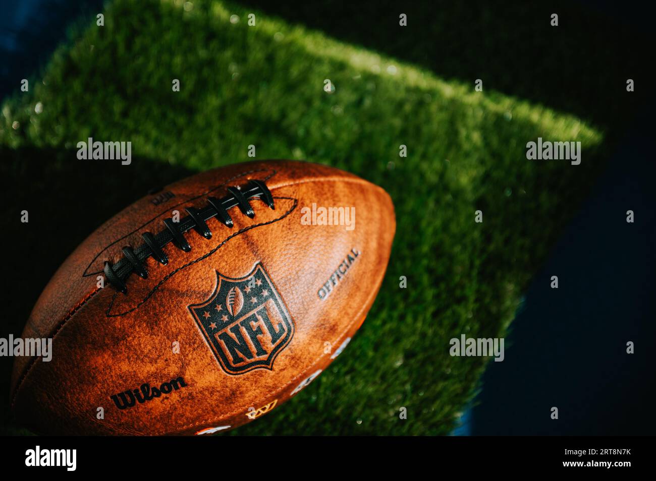 NEW YORK, USA, SEPTEMBER 11, 2023: NFL's Trademark: Leather Ball and Iconic Logo. Green Grass in background, black edit space, national football leagu Stock Photo