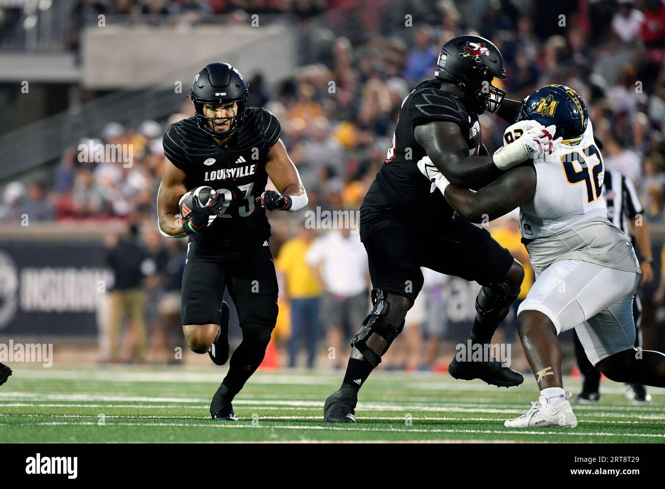 Louisville running back Isaac Guerendo (23) runs through an opening in