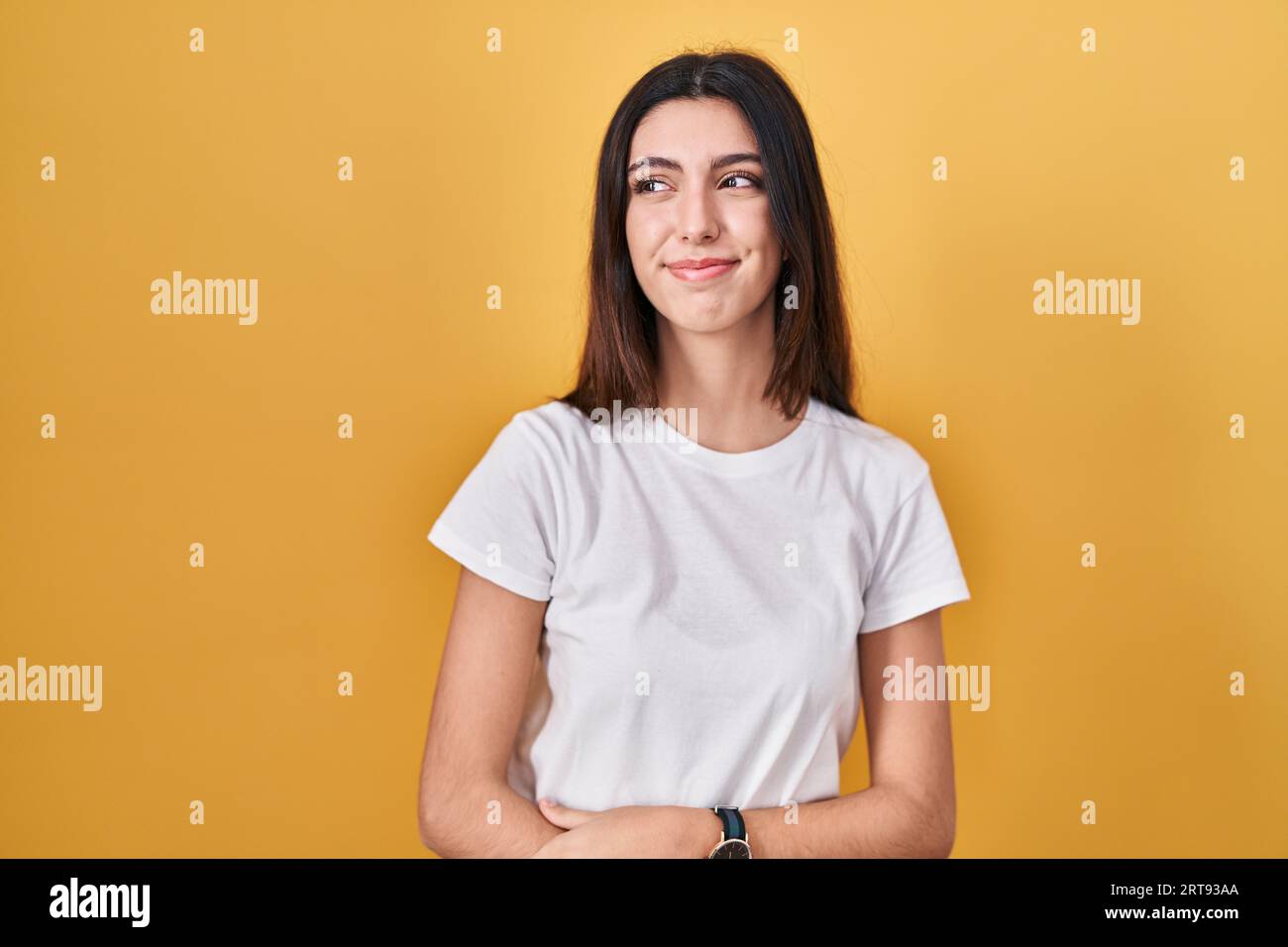 Young beautiful woman standing over yellow background smiling looking ...