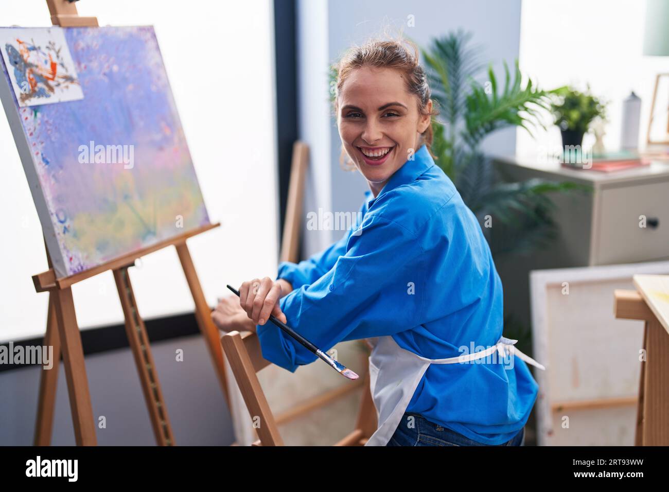 Young woman artist smiling confident sitting on chair at art studio ...