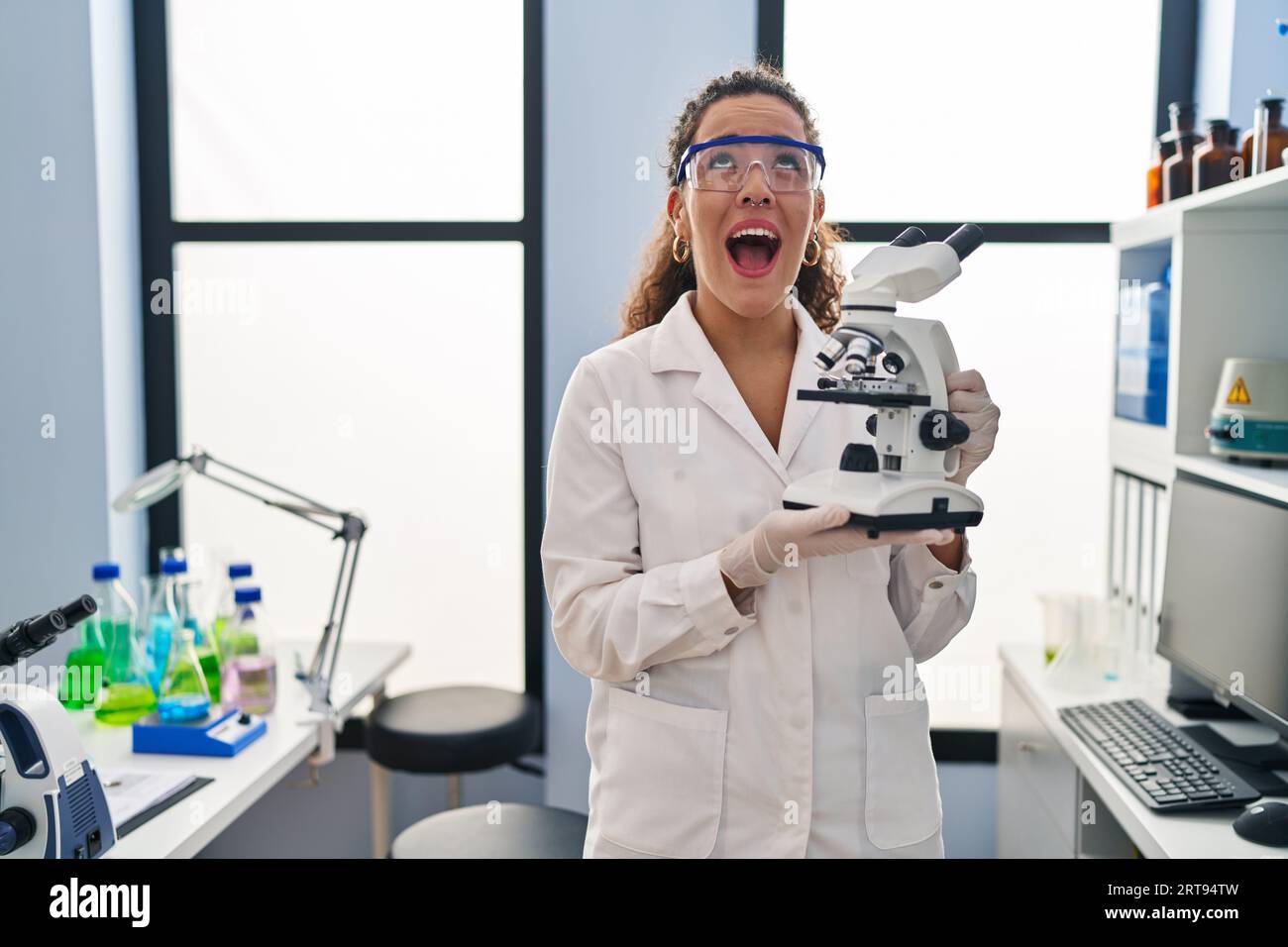 Young hispanic woman working at scientist laboratory angry and mad ...