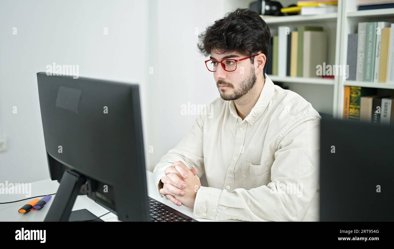 Young hispanic man student using computer studying at library ...