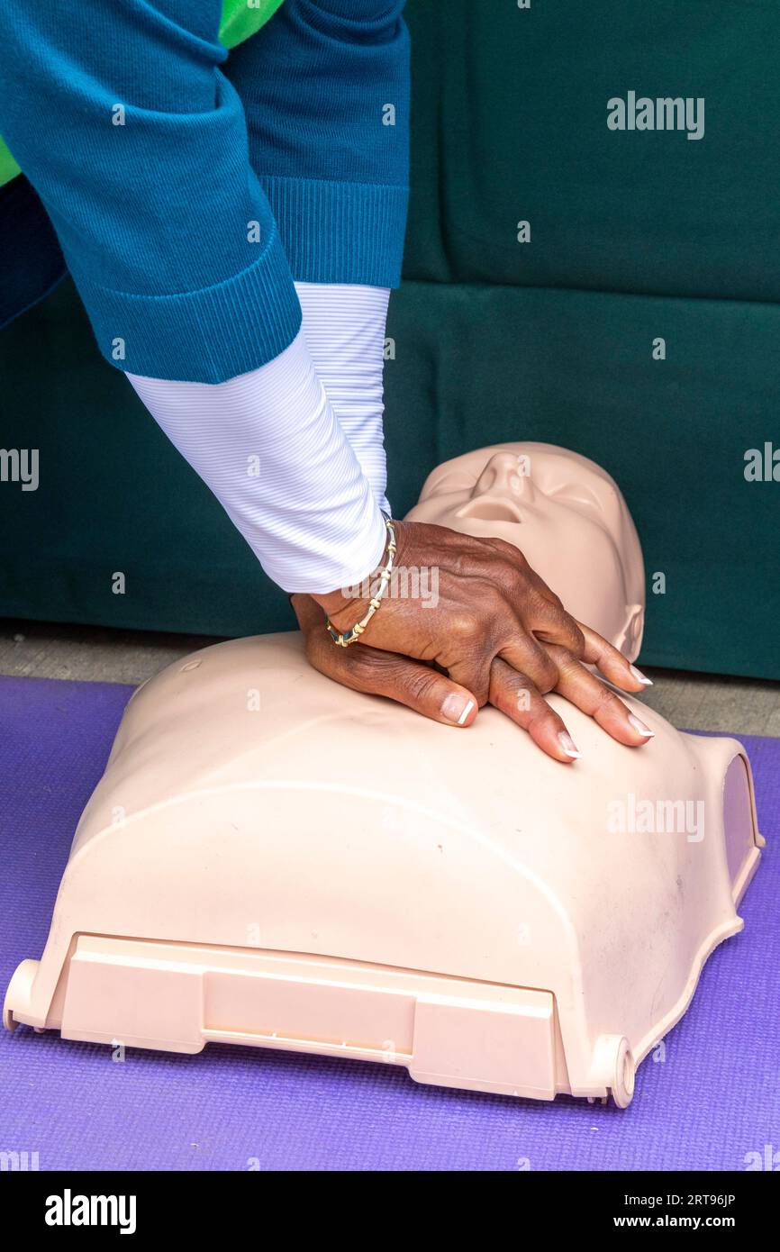 Detroit, Michigan - At a block party sponsored by the Detroit Health Department, a woman learns how to help a victim of sudden cardiac arrest using ca Stock Photo