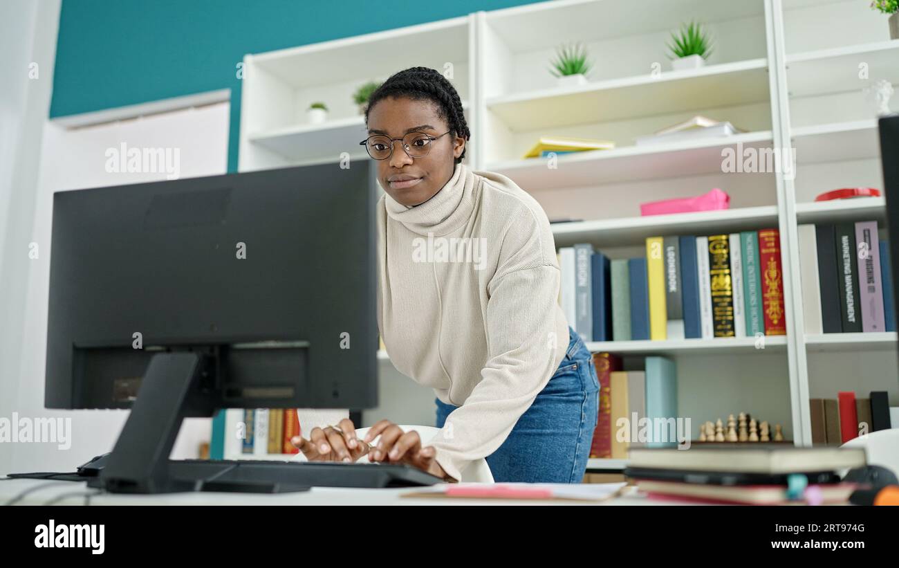 African american woman student using computer studying at library ...