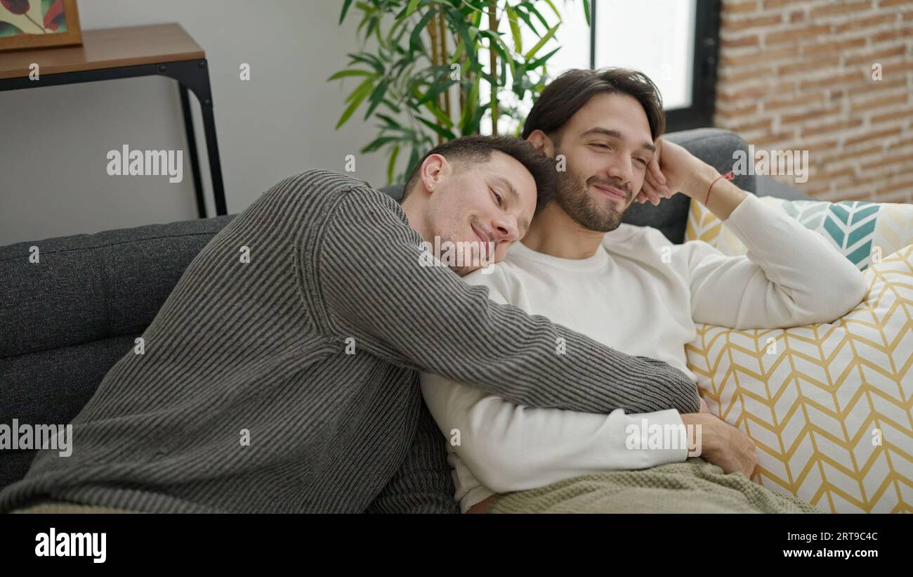 Two men couple hugging each other sitting on sofa at home Stock Photo ...