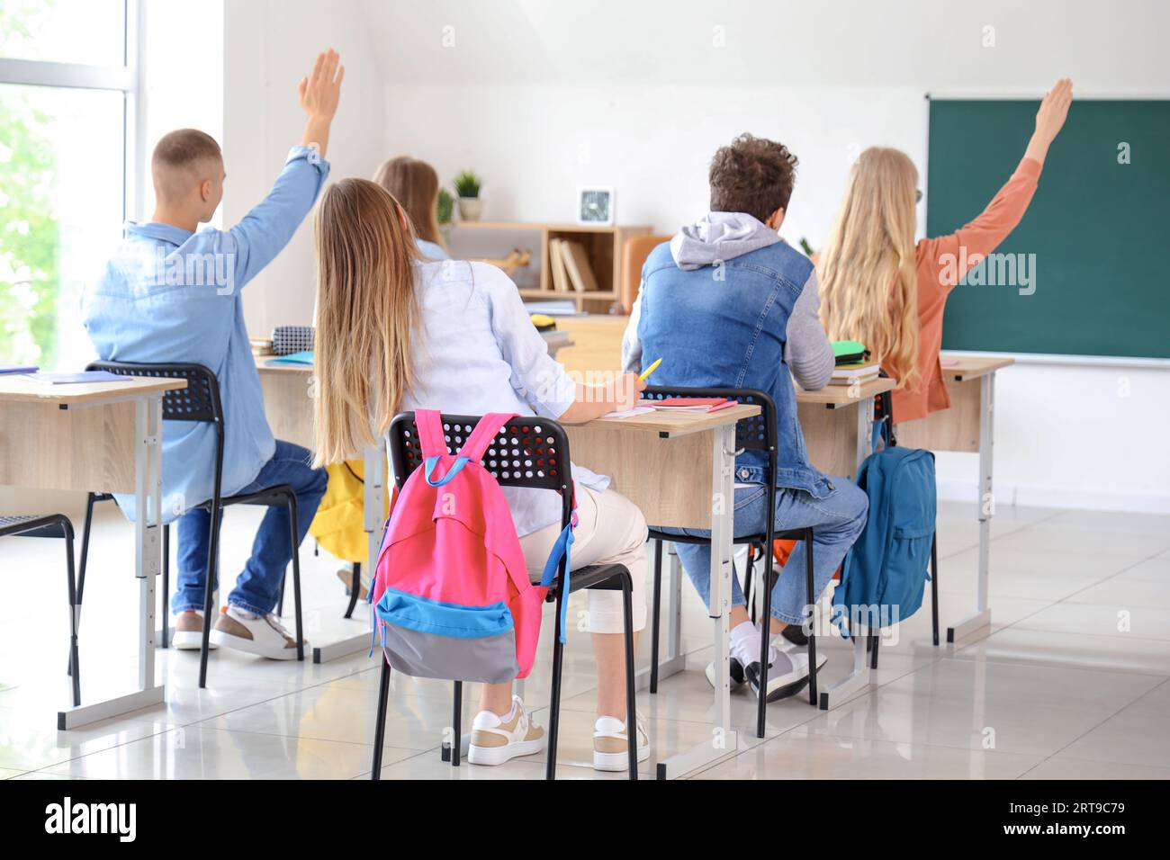 Teenagers in classroom raising hands hi-res stock photography and ...