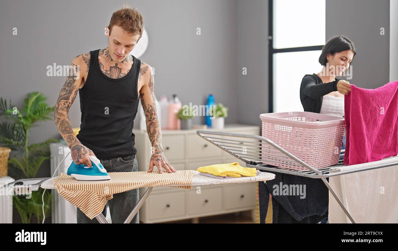 Beautiful couple doing chores together at laundry room Stock Photo - Alamy