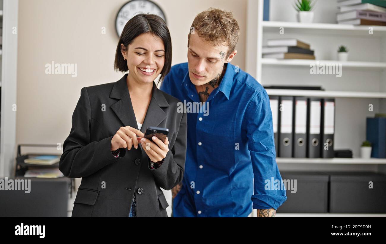 Two business workers using smartphone working at the office Stock Photo