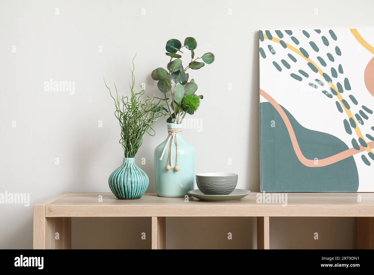 Vases with green plants on wooden cabinet near white wall Stock Photo ...