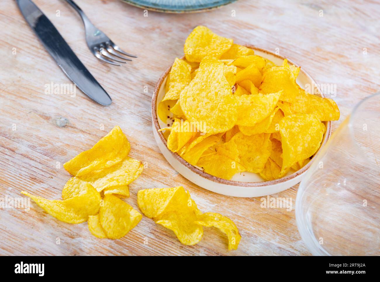 Plate of crispy deepfried chips of thinly sliced potatoes Stock Photo