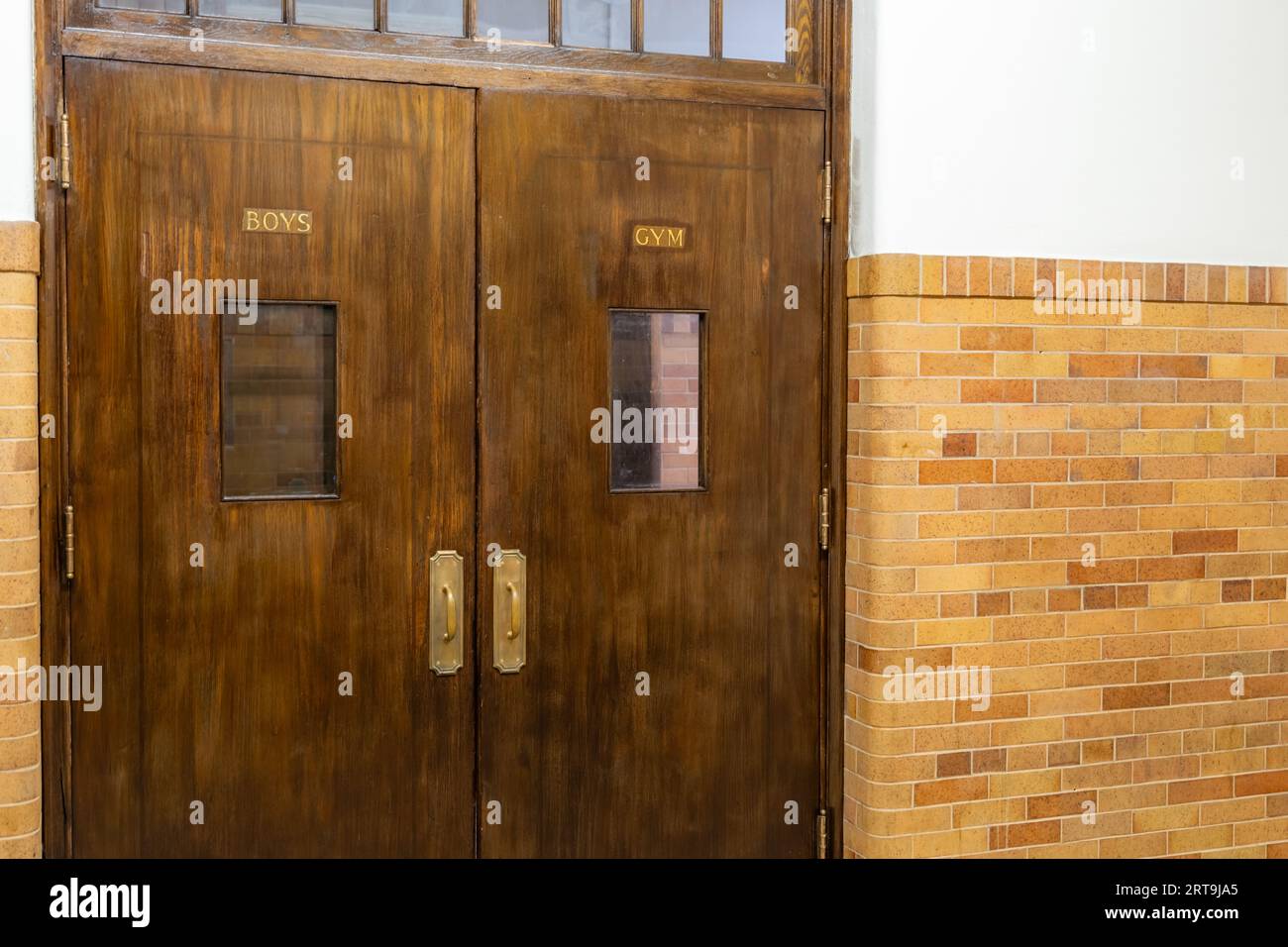 Empty hallway with boys gym double wooden doors in a school. Stock Photo