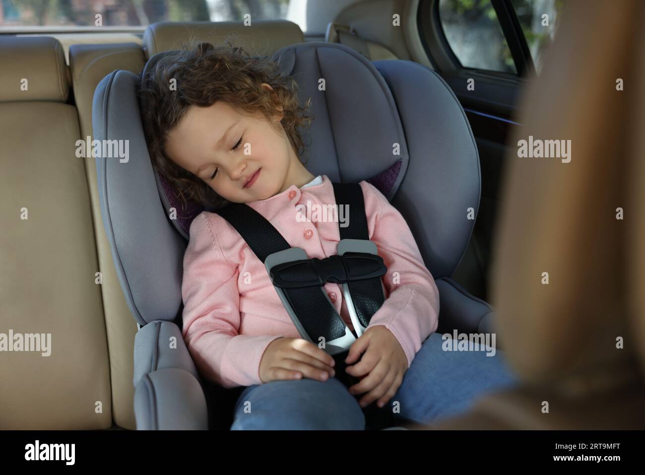 Cute little girl sleeping in child safety seat inside car Stock Photo