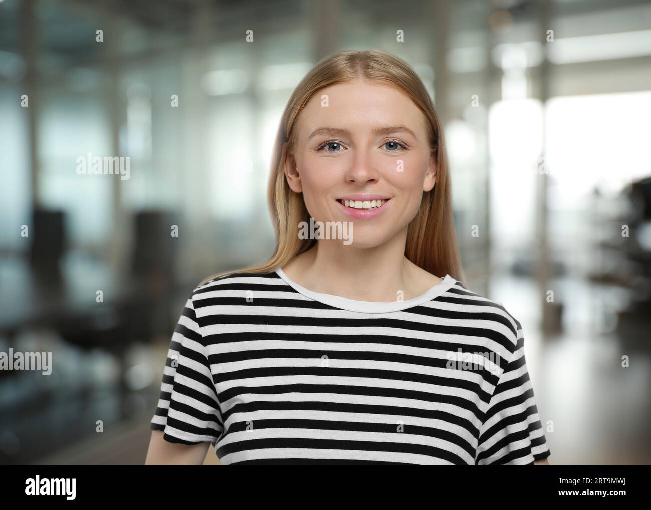 Portrait of happy woman in office. Pretty girl looking at camera and smiling on blurred background Stock Photo