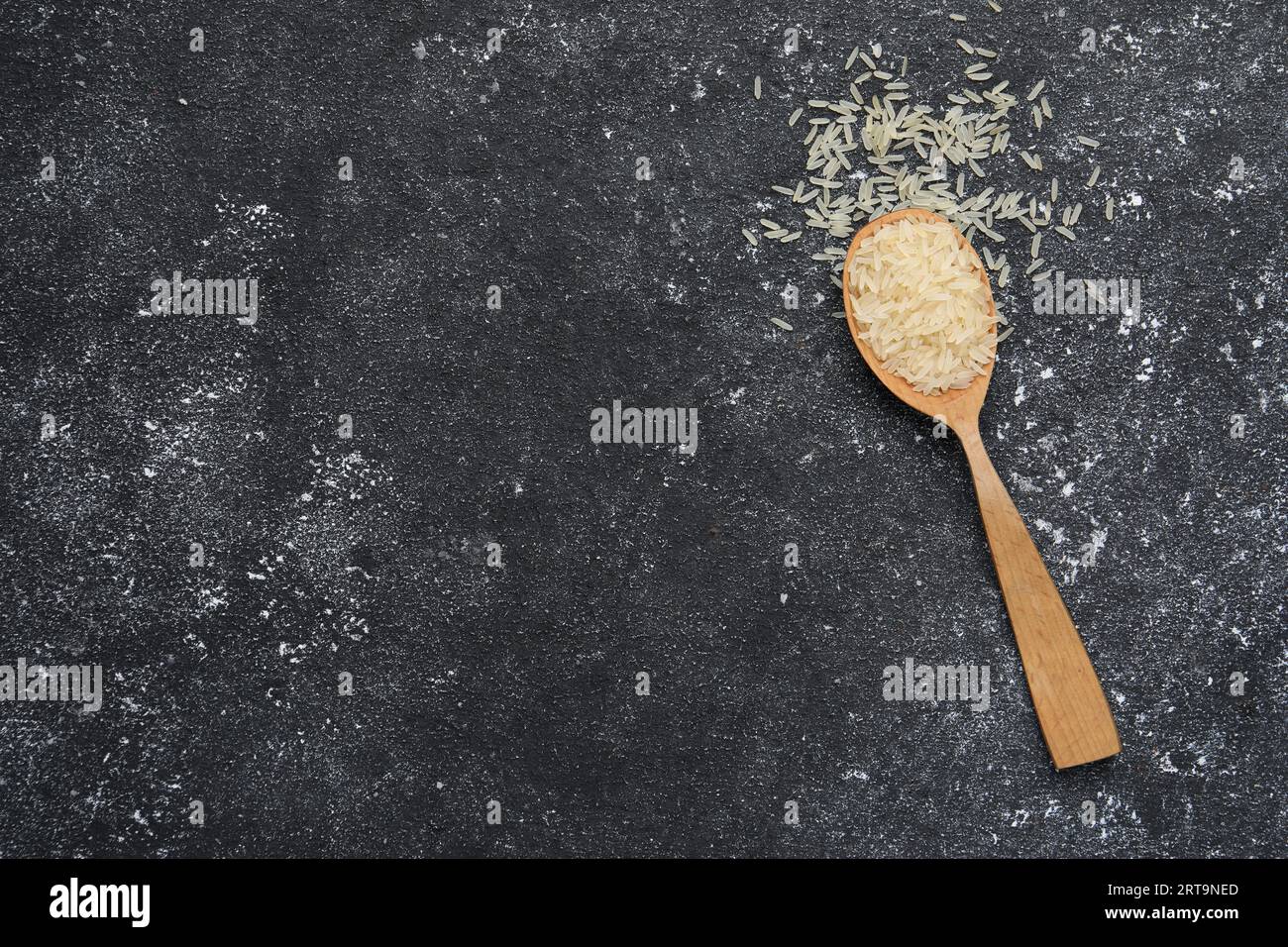 Texture Rice Spoon Spoon with raw rice on black textured table, top view. Space for text ...