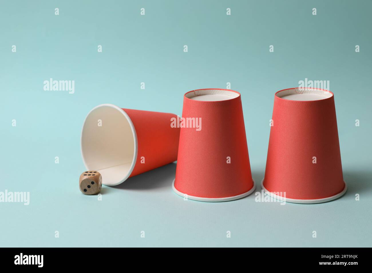 Three red cups and dice on light blue background. Thimblerig game Stock ...