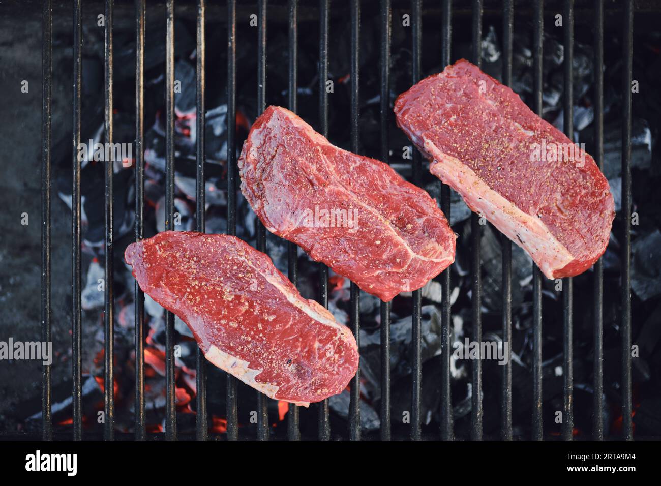 Top view of beef strip steaks on grid of grill Stock Photo