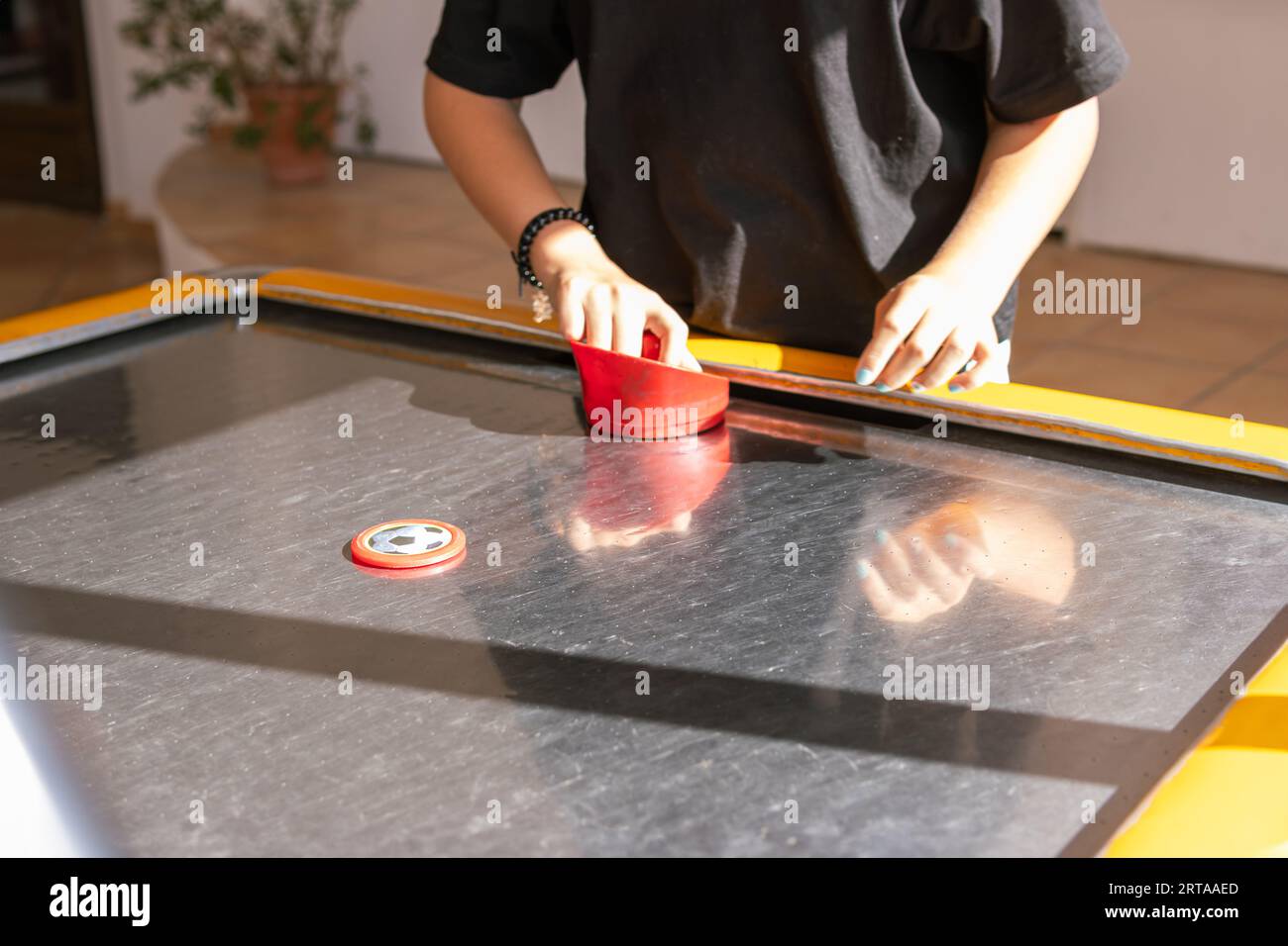 Hands of young people holding striker on air hockey table. Friends
