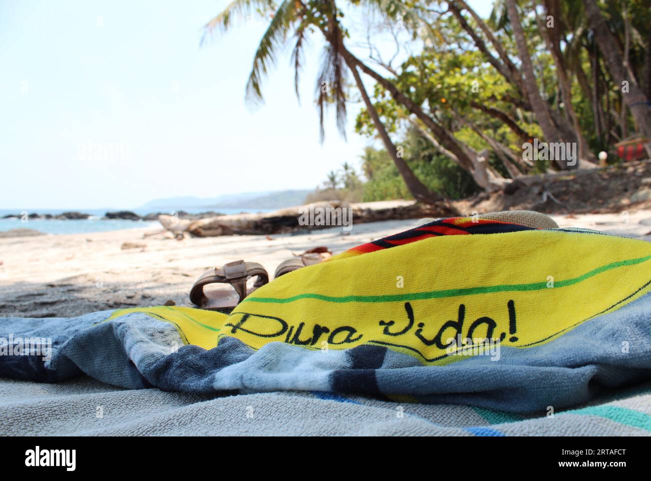 Enjoying life at a paradise beach in Costa Rica, 'pura vida!' on the beach towel means “simple life” or “pure life,” but in Costa Rica it is more than Stock Photo