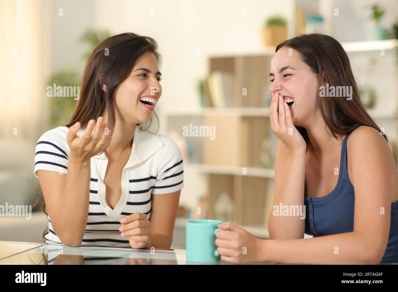 Happy embarrassed woman laughing on conversation covering mouth at home Stock Photo