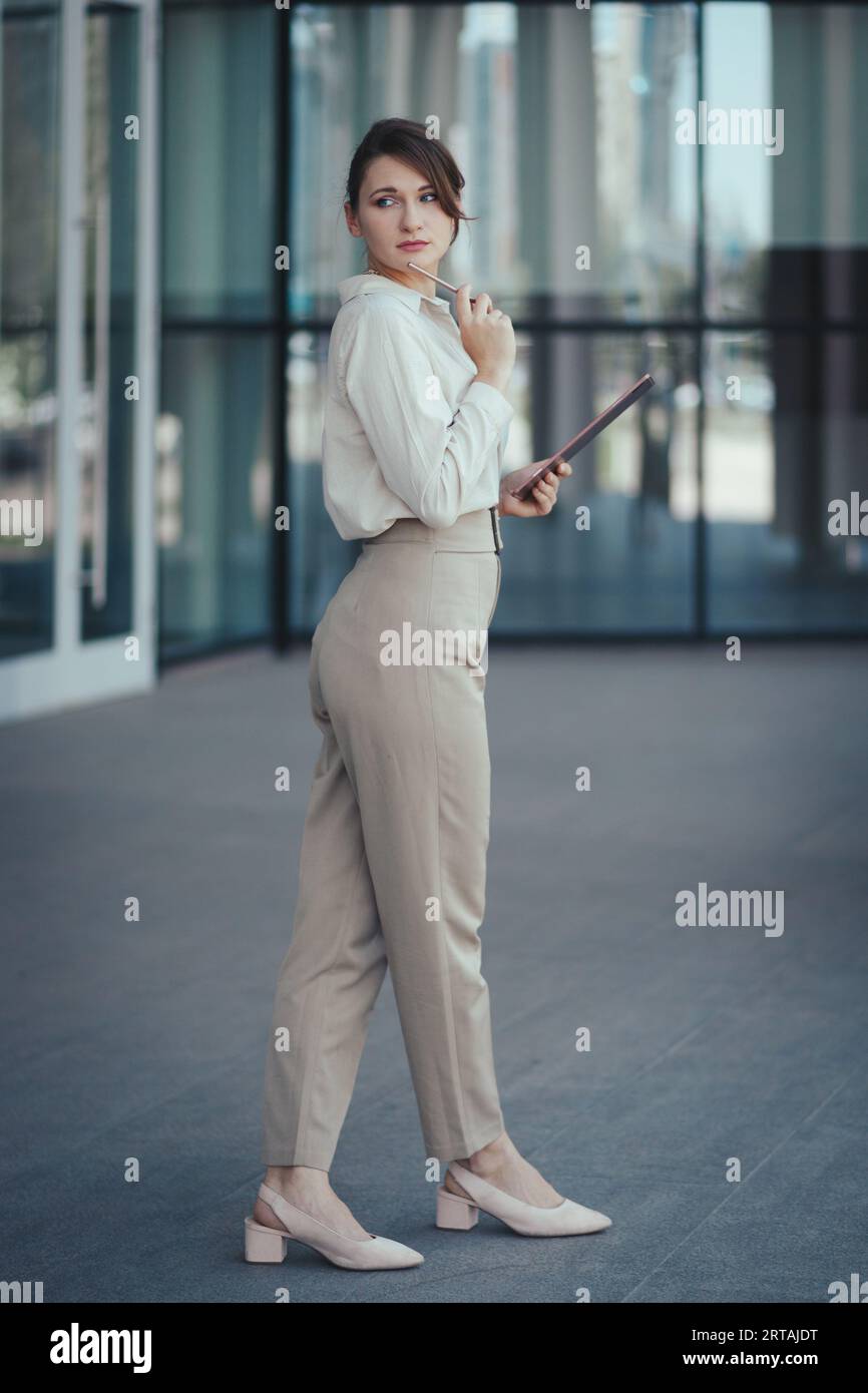 Young caucasian cute business woman in office fashion style pantsuit in  beige tones with digital tablet in hands posing near office building Stock  Photo - Alamy