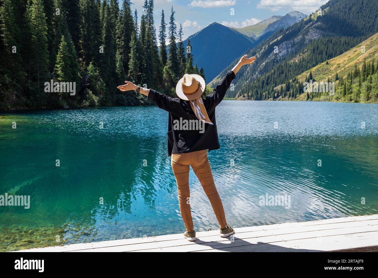 A woman tourist delighted with Kolsay lake in Kolsai Koldery gorge, nature of Kazakhstan National Park Stock Photo