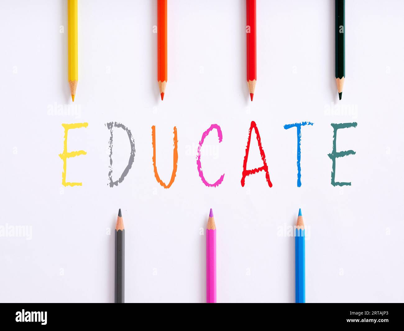 The handwritten word educate and colorful crayons on white background. Preschool education concept. Stock Photo