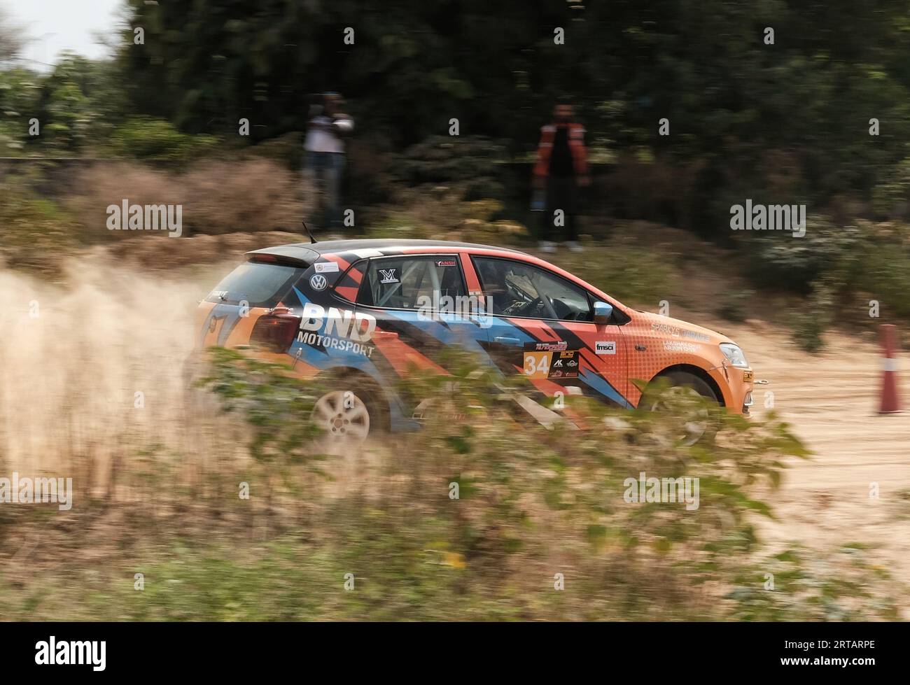Orange Volkswagen Polo being driven through an autocross stage on dirt Stock Photo