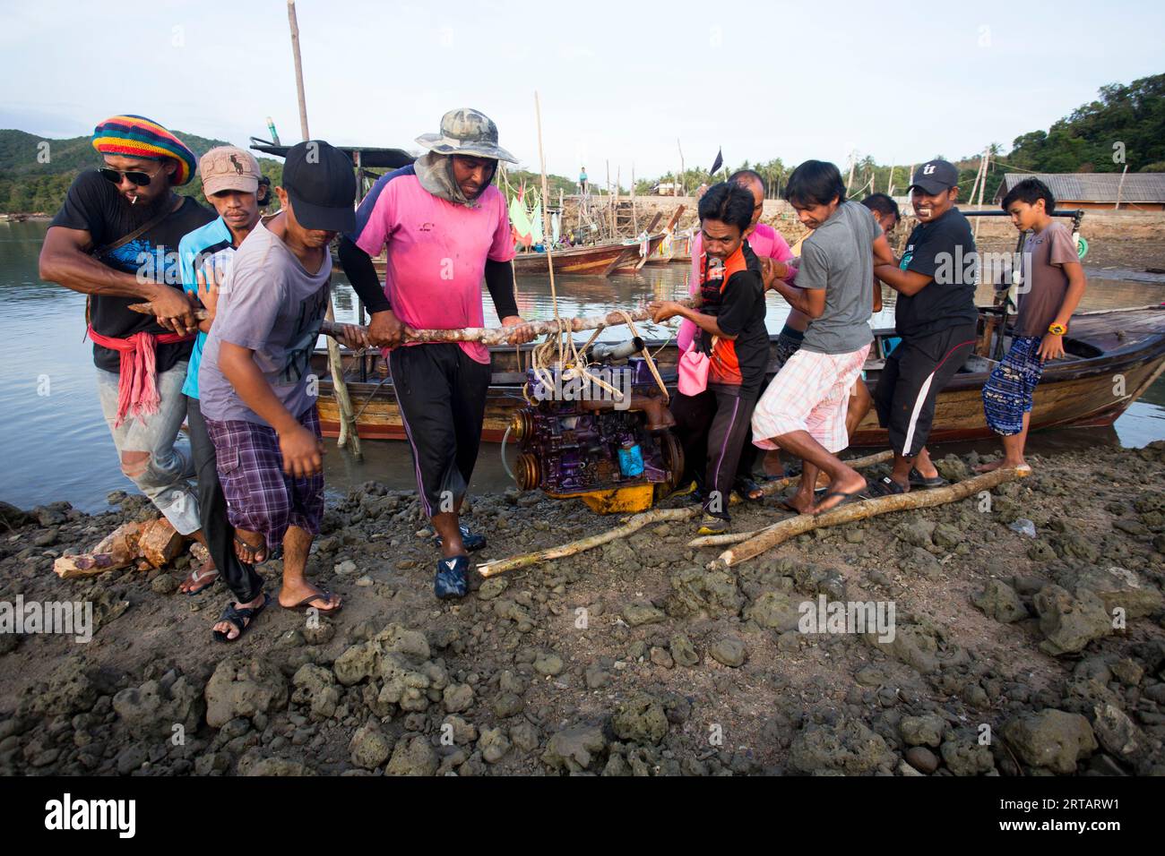 Koh Yao, Thailand; 1st January, 2023: A group of Thai fishermen loading the engine of a boat. Stock Photo