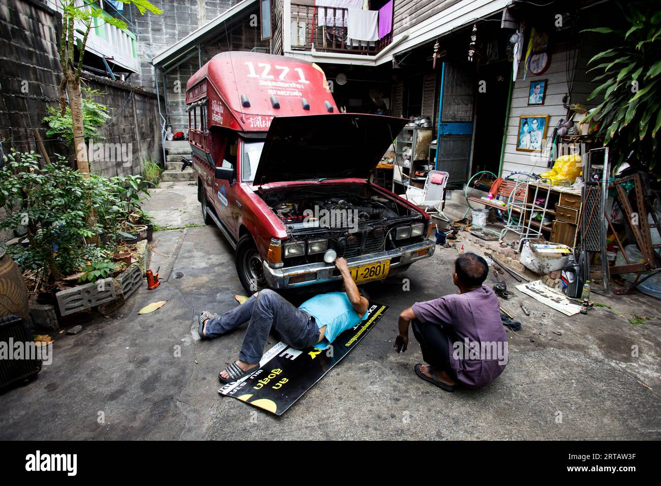 Bangkok, Thailand; 1st January 2023: Two men fixing a red van. Stock Photo