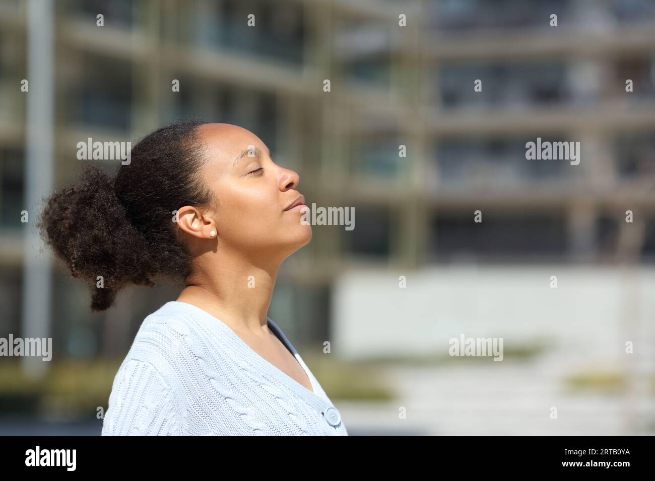 Profile of a black woman breathing fresh air in urban scene a sunny day ...